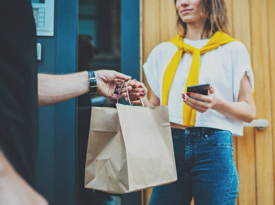 Lieferdienst bringt Kundin bestelltes Essen in einer braunen Papiertüte