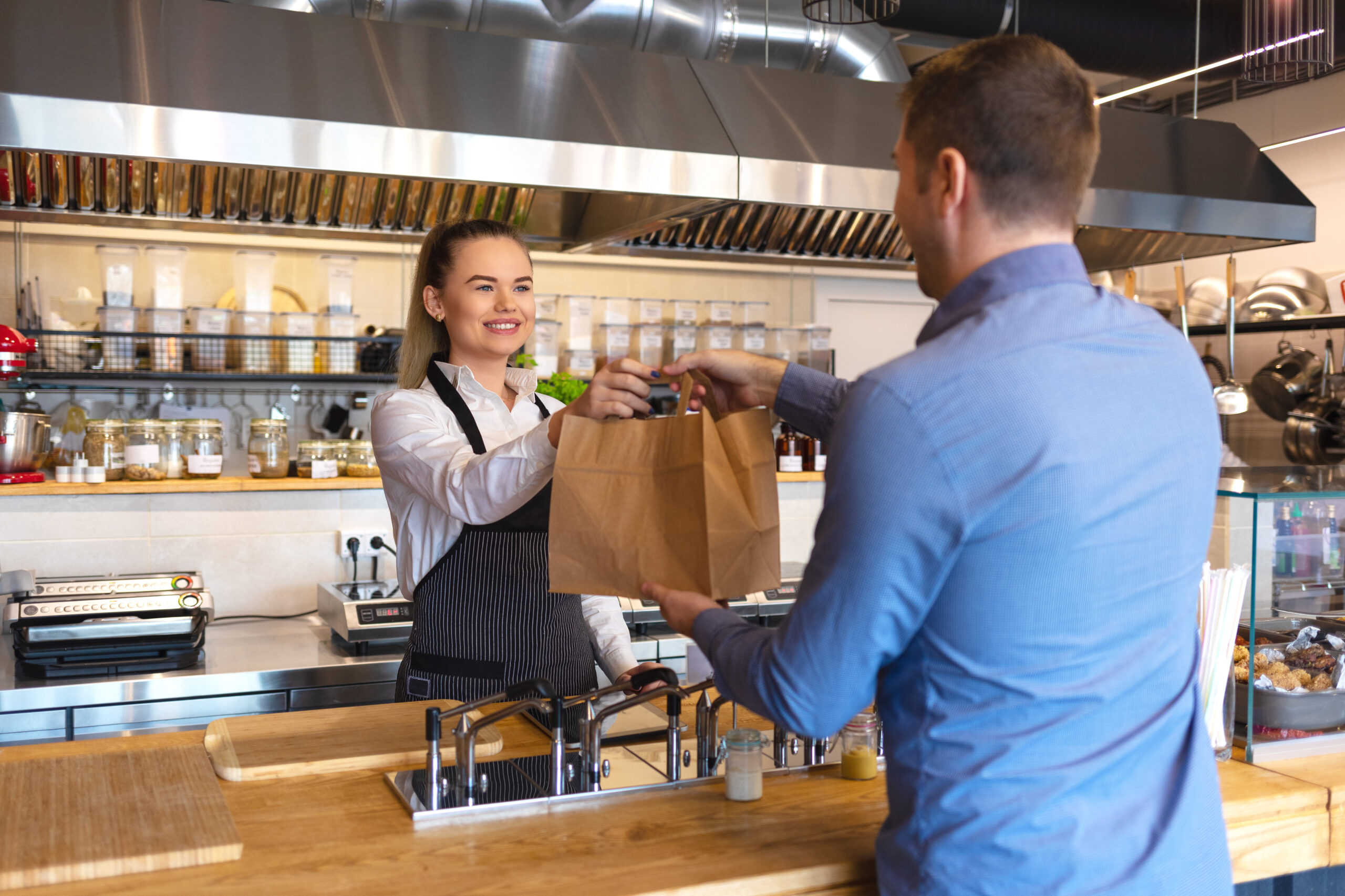 Kunde nimmt Essen aus dem Restaurant in Papiertüte am Tresen entgegen